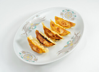 Delicious pan fried gyoza dumplings presented on a vintage plate ready to serve a tasty meal or snack for sharing and enjoying