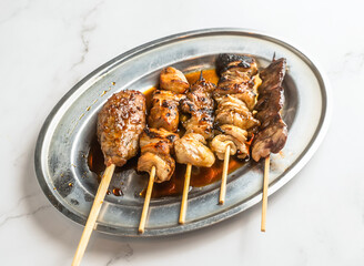 Delicious grilled yakitori skewers glistening with sauce on a silver platter, perfect for Japanese cuisine promotions and food blog content