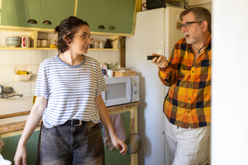Middle-aged man in glasses and young woman talking in the kitchen while preparing food