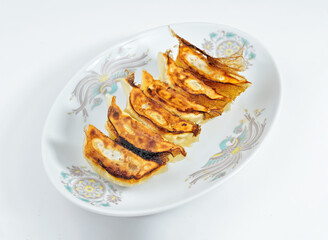 Crispy golden pan-fried gyoza dumplings on a decorative plate ready to be enjoyed for a delicious Asian inspired meal