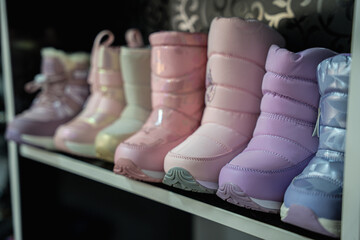 A display of various colorful winter boots for children, showcasing different styles and shades, perfect for cold weather fashion.