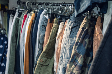 A collection of various pants hanging on display, showcasing different colors and styles in a retail setting.