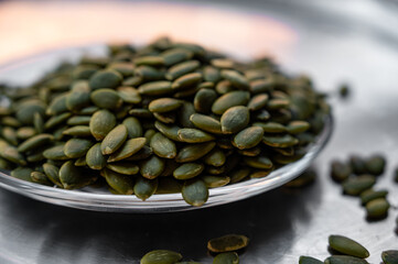 Shelled pumpkin seeds close-up on a small plate – healthy snack concept