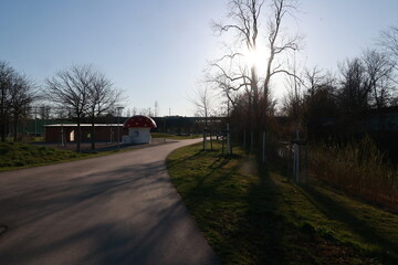 A red building with a mushroom shaped roof is in the foreground of a park