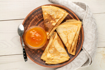 Hot pancakes with apricot jam on a wooden table, macro, top view.