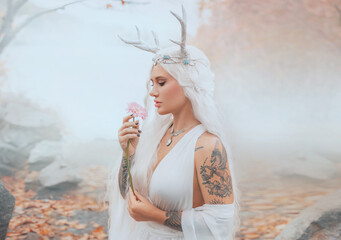 art photo real person fantasy young elf woman holding pink gerbera flower. close-up beauty face sexy eyes lips fairy tale girl, blonde ash hair white dress trendy make-up. myth faun pixie sexy lady 