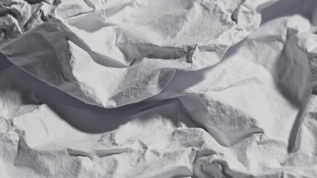 Abstract crumpled paper moves and shifts in a textured dance of light and shadow footage