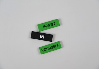 three colorful wooden blocks spelling 'Invest In Yourself' against a bold white backdrop. Perfect for themes of self-improvement, motivation, and personal growth in wellness and education materials.