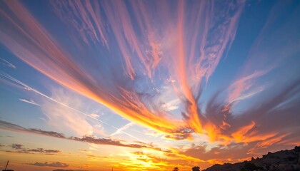 Expansive view of streaking cirrus clouds at sunrise, with orange hues at horizon
