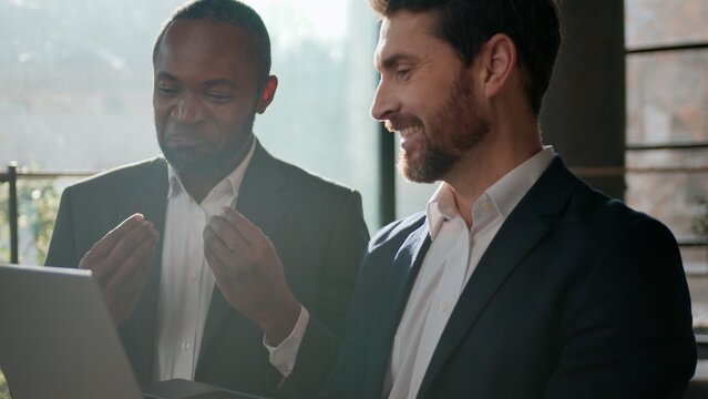 Two smiling men diversity businessmen business team with laptop talking enjoying pleasant communication work with computer Caucasian businessman expert showing idea consulting African American leader