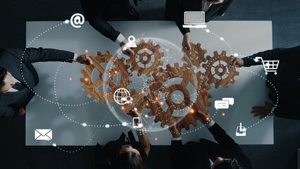 Dynamic business team collaborating over a table with gears and digital elements, showcasing teamwork, innovation, and technology in a professional environment. Raster