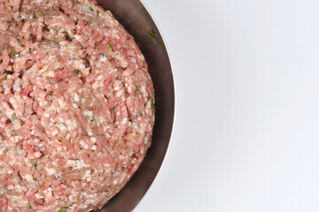 A stainless steel bowl filled with freshly ground and seasoned raw pork for sausages occupies the left side of the frame, leaving a large, clean white copy space to the right