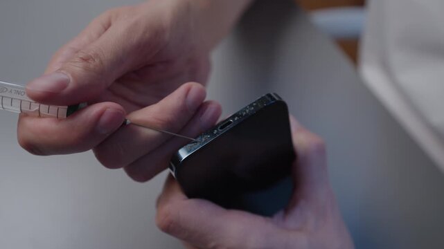 Serviceman hands cleaning smartphone charging port using syringe needle, emphasizing precision and attention to detail involved in device maintenance, service and repair, close-up, slow motion.