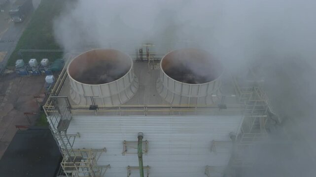 Aerial view of two industrial cooling towers expelling steam into the atmosphere, creating a misty, ethereal scene, Bury Saint Edmunds, England, United Kingdom.