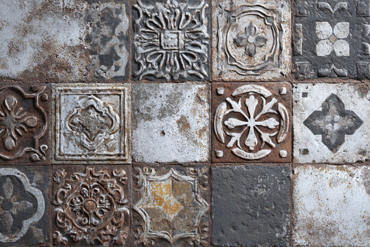 Rustic weathered tiles with intricate floral and geometric patterns arranged in a grid showcasing a vintage aesthetic with a textured surface - Powered by Adobe