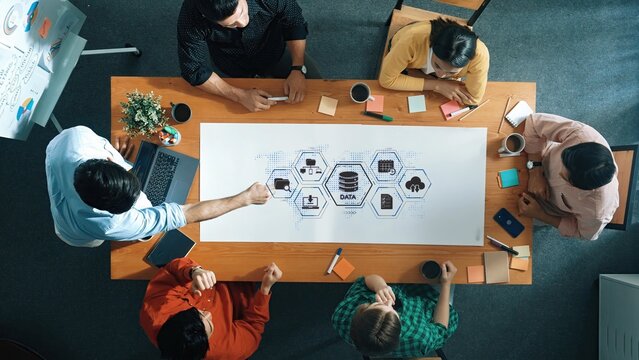 A diverse team collaborates on a data analysis project, exchanging ideas and insights over charts and graphics in a modern workspace, showcasing teamwork and innovation. Raster - Powered by Adobe