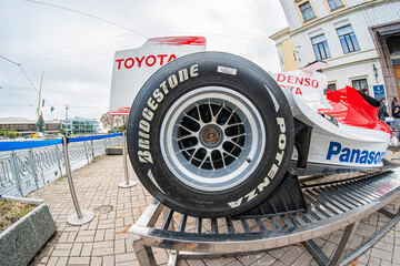 Obraz premium Formula 1 Toyota TF-108 car on wheel stand, primarily red and white with sponsor logos Aerodynamic design, outdoor setting near a race track, natural lighting with - Kyiv, Ukraine 10-10-2024