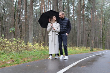 Fototapeta premium Couple under an umbrella on a wet forest road
