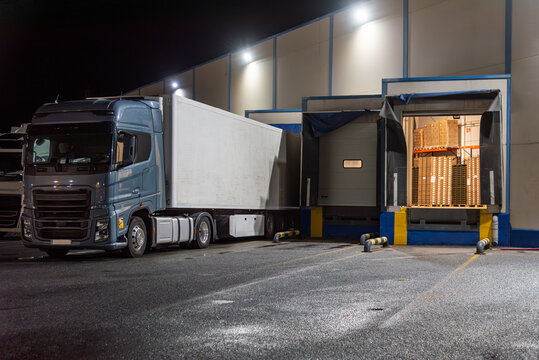 Several loading docks with trucks backed up and an open dock door showing palletized goods