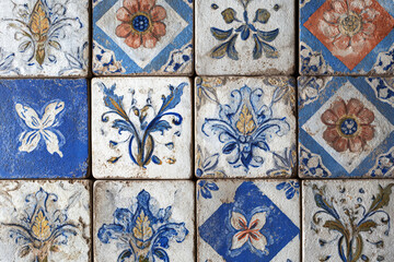 A collection of vintage ceramic tiles showcasing intricate floral and butterfly motifs in blue orange and yellow hues