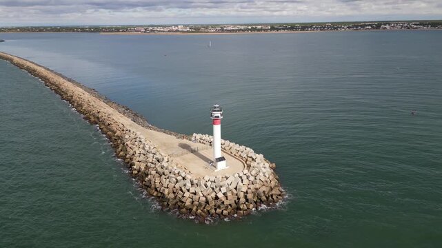 Aerial view of the Faro de El Espigon lighthouse on a pier, its red and white contrasting against the blue water, Huelva, Andalusia, Spain.