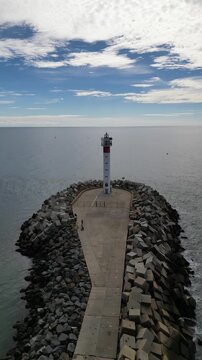 Aerial view of the tall Faro de El Espigon lighthouse standing proudly at the end of the pathway surrounded by the sea, Huelva, Andalusia, Spain.