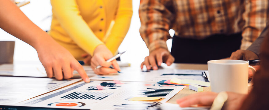 A diverse team collaborates in a bright office, analyzing data and discussing strategies. Colorful sticky notes and charts enhance the creative atmosphere of teamwork. SACTR