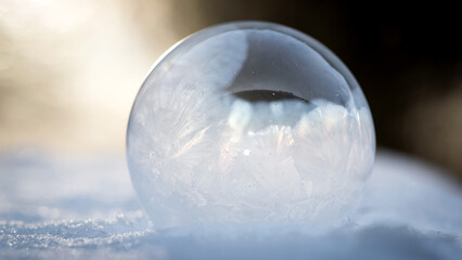 A frozen bubble in the snow. Beautiful frosty patterns on a frozen soap bubble. winter, frosty background. Frozen bubble. soap bubble on snow close up. winter season, cold time. macro photo