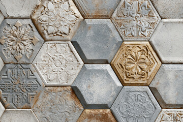 Hexagonal tiles with carved floral patterns and textured surfaces in earthy tones