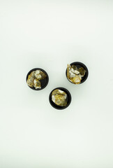 Overhead clean composition of whole yellow potatoes covered in heavy mold layers, captured on a black wooden tabletop with strong diagonal shadows.