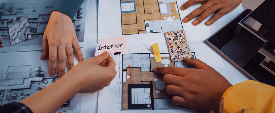 A group of individuals collaborates on interior design plans, showcasing hands selecting color samples and discussing layout details over blueprints and design visuals. SACTR - Powered by Adobe