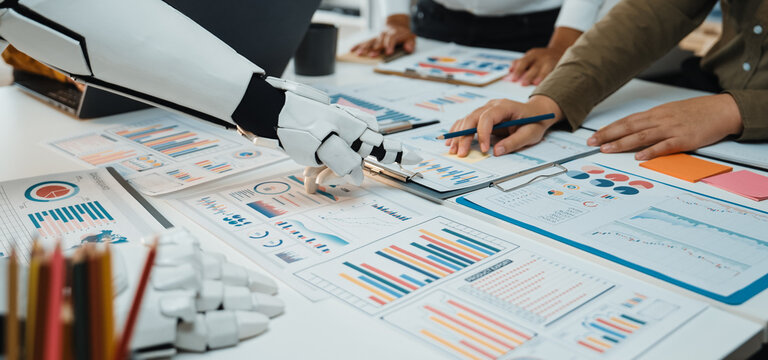 A robotic arm aids a business team in analyzing data and developing strategies. The scene depicts modern collaboration with charts, graphs, and documents spread across a table.Noogenesis - Powered by Adobe
