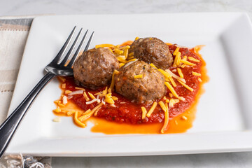  three meat balls with shredded cheese and sauce