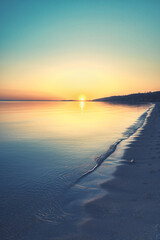 A calm sunset over the evening sea: soft light, gentle waves and golden sky on the horizon.