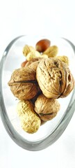 Close-up of walnuts, peanuts and hazelnuts inside a glass dish. Rustic organic snack with natural textures, ideal for healthy lifestyle content, packaging, Christmas food 