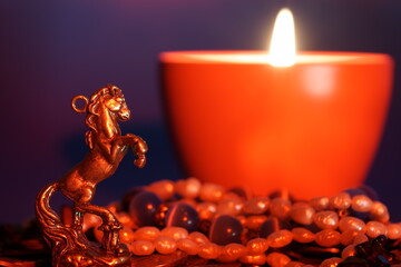 Metal statuette of a horse and jewelry. There is a candle flame nearby.