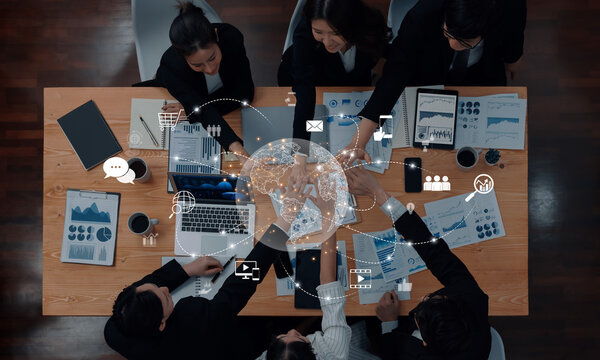 A group of professionals engaged in a collaborative business meeting, utilizing technology for data visualization and global connectivity in a modern office setting. Trope - Powered by Adobe