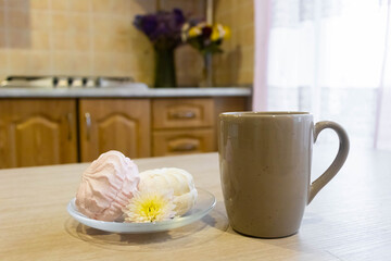Warm drink and sweet treats on a kitchen table set in a cozy home, featuring a cup and desserts in a relaxed afternoon setting