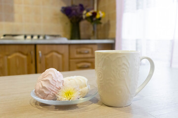 Delicious meringue dessert served with a cup of steaming beverage in a cozy kitchen setting with natural light in the background