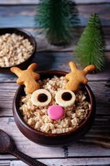 Oatmeal in a bowl in the form of reindeer for Christmas holidays on a wood background