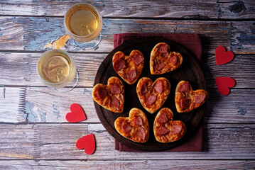 Pizza mini with salami in the form of hearts for Valentine's day holiday on a wood background