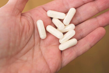 Human palm filled with pale capsules, symbol of self medication and overdose risk, healthcare responsibility, medical advice, pharmaceutical safety campaigns and educational content