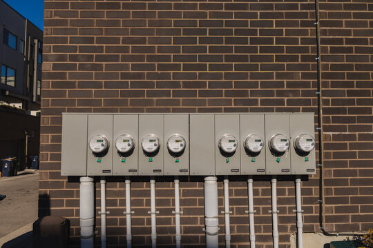 Row of smart electric meters on brick wall measuring residential energy consumption