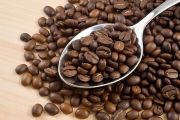 Fototapeta premium Roasted Coffee Beans Overflowing from a Silver Spoon Ready for Grinding and Brewing a Perfect Cup
