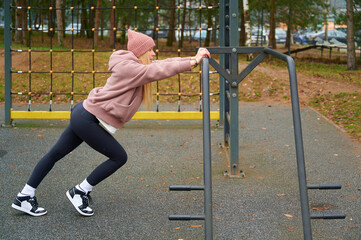 Fototapeta premium Young woman stretching legs on an outdoor sports ground