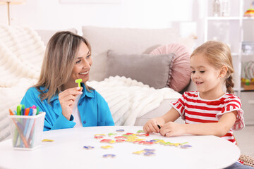 Fototapeta premium Mother teaching her daughter alphabet at white table indoors