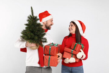 Happy couple with Christmas tree and gifts on white background