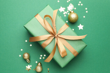 Beautiful Christmas composition with gift and decor on green background, flat lay