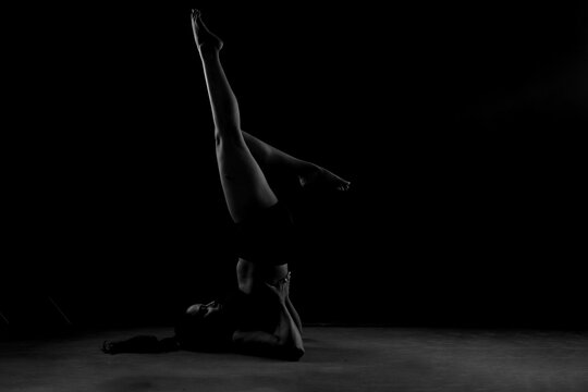 Dramatic silhouette of a woman performing an yoga . Artistic black and white studio fitness photography with rim lighting. - Powered by Adobe