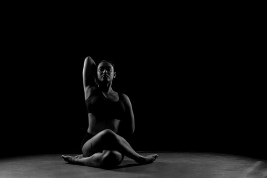 Dramatic silhouette of a woman performing an yoga . Artistic black and white studio fitness photography with rim lighting. - Powered by Adobe